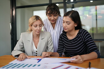 Obraz premium Businesswoman in group meeting discussion with other businesswomen colleagues in modern workplace office with laptop computer and documents on table.