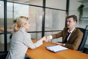 Portrait of smiling young woman shaking hands with HR manager at job interview in office, copy space