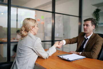 Portrait of smiling young woman shaking hands with HR manager at job interview in office, copy space