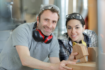 carpenter training female apprentice to use mechanized saw