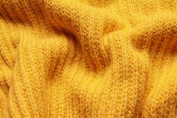 Close-up abstract texture yellow color fabric cloth textile background, knitted wool wavy material, soft folds waves on the fabric. Macro, web theme, template, wallpaper, concept design