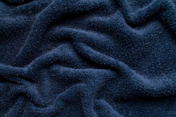 Fototapeta na wymiar Close-up abstract texture dark blue color fabric cloth textile background, terry cotton wavy material, soft folds waves on the fabric. Macro, web theme, template, wallpaper, concept design