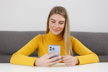 Happy blonde female browsing mobile app on modern blue smartphone. Cheerful Ukrainian girl using cellphone for communication