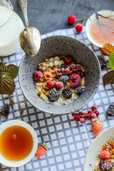 Oatmeal with raisins and frozen berries on a dining table with a checkered napkin.