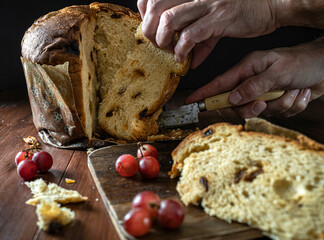 Man's hand cutting a piece of Panettone. Warm colours and Christmas atmosphere.