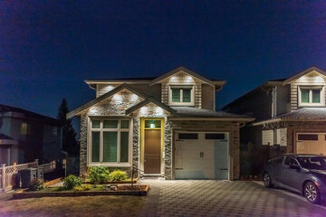 house with garage door, big tree and nice landscape at night