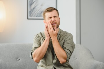 Man suffering from strong toothache. Upset male patient with inflamed nerve, tooth abscess, or...