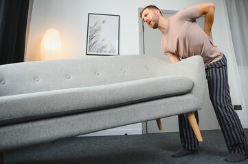 Young man suffering from back pain after carrying heavy furniture.
