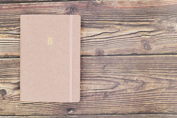 New agenda for the year 2023 with gold-colored writing on an antique pink soft suede cover, placed...