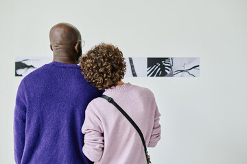Rear view of young couple watching at modern art together at gallery