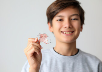 Dental braces. Teenager boy smiling holding orthodontic appliance dental treatment to improving...