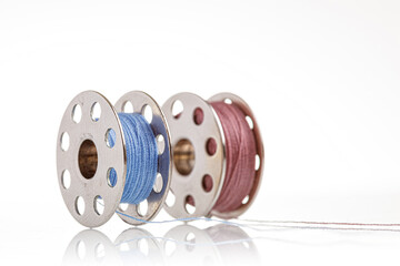 spools of blue and pink thread on a white background