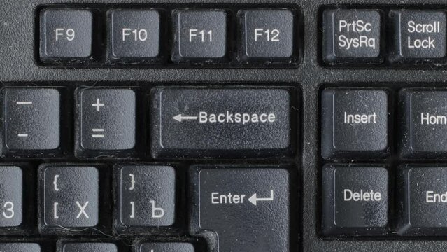 A male finger presses the backspace key on a computer keyboard once and holds it, macro