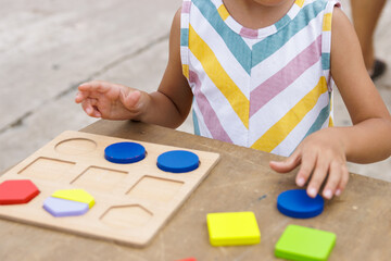 Little girl making colorful wooden puzzle