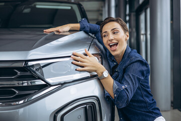 Woman hugging a new car in a car showroom