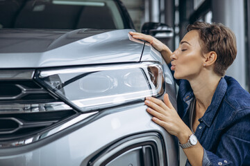 Woman hugging a new car in a car showroom