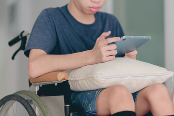 Young man with a disability using mini laptop for learning or studying with remote in living room...