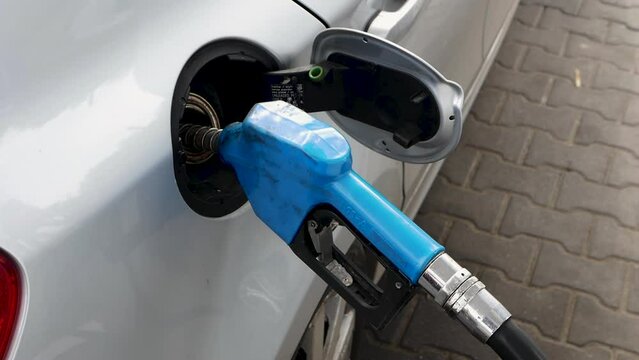 A man fills up a car with gasoline at a gas station by inserting a gasoline hose into the auto tank. Fill the halon with gasoline from the hose.