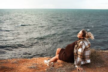 Beautiful pregnant woman sresses in a knitted dress walks along the seashore in a windy weather