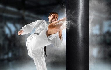Karate master in white kimono at the moment of impact on punching bag