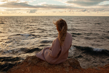 Beautiful pregnant woman sresses in a knitted dress walks along the seashore in a windy weather