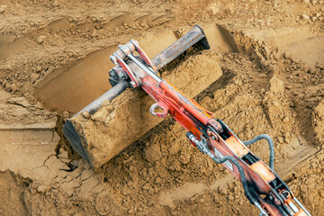 Large excavator bucket rakes sand for construction work