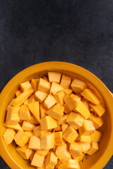 Freshly chopped pumpkin into cubes in a colander on a worktop. Top view.