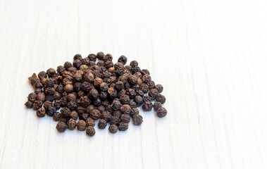 Closeup of Dry Black Pepper Isolated on White Wooden Background with Copy Space