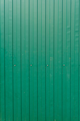 Green metal surface. Texture. Fence with rivets close-up