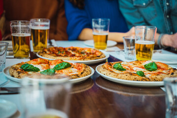 Pizzas and beer in glasses on a wooden table friends have pizza party after work
