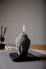 Statuette with candlestick. Statue of Buddha, incense sticks and burning candle. Aromatherapy, home fragrance. Concept of home relaxation and anti stress, zen buddhism.