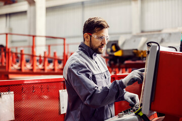 A heavy industry worker controls the machine and looks at the display while standing in the...