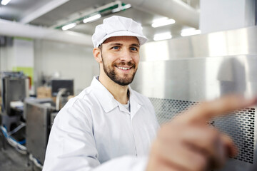 A happy dairy worker programs a machine for milk pasteurization.