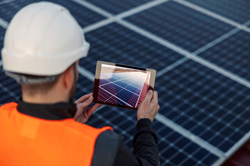 Rear view of worker taking picture of solar panels.