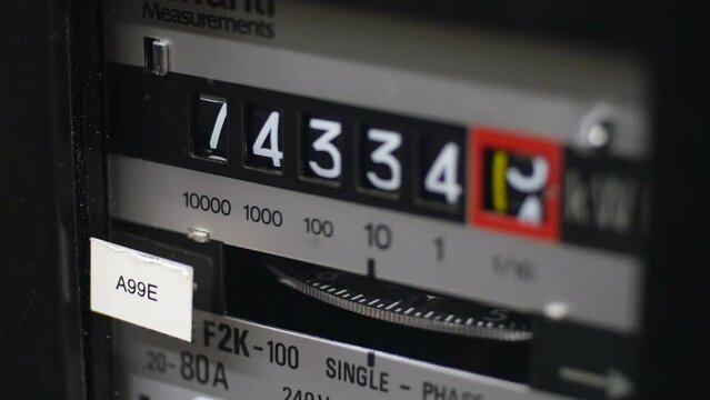 A close-up of an electric meter and digits. A turning dial showing energy in use. Concept for cost of living crisis, fuel bills, inflation and high bills. Static shot.