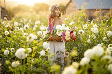 Portrait of a woman with lots of freshly picked up colorful dahlias and lush amaranth flower on...