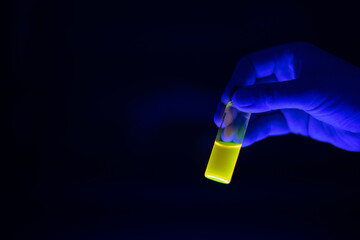 A researcher holding chemistry photochemical reaction green glass vials in a organic laboratory. A copy space black background.