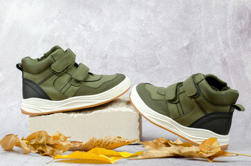 Demi-season shoes on a white stone podium. Stylish children's green shoes