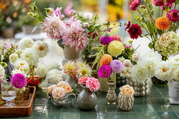 Lots of different cuted flowers in vases on the table outdoors