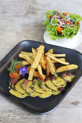 Bistro Steak Frites with salad served in a dish isolated on grey background side view