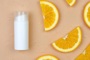 Cosmetics with orange. Orange Moisturizer. Blank white cosmetic tube and orange slices on a beige background.