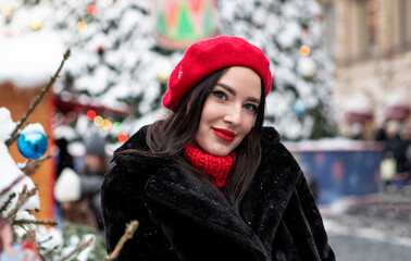 beautiful girl in a red beret and mittens in winter on New Year's street.