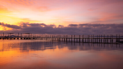 Wooden jetty on Carmoli beach at a beautiful and colorful sunrise, in Cartagena, Region of Murcia, Spain