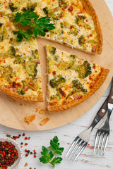 Quiche Lorraine with chicken and broccoli on marble background close-up. Pie with vegetables, poultry, cheese, parsley and spices. Traditional French food. Selective focus, top view