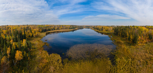 Looking over a pond reflecting the clouds and surrounding brightly colored fall trees