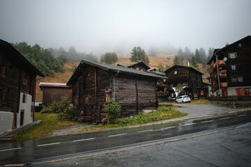 Ancient wooden traditional Swiss raccard granary on stone piles in old Hinterdorf quarter of Zermatt Switzerland, Rainy weather.