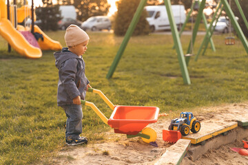 Child play with wheelbarrow in sandbox, dreams to be an engineer. Little builder. Education, and imagination, purposefulness concept. boy with wheelbarrow