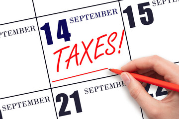 Hand drawing red line and writing the text Taxes on calendar date September 14. Remind date of tax payment