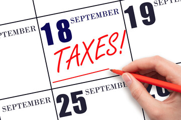 Hand drawing red line and writing the text Taxes on calendar date September 18. Remind date of tax payment