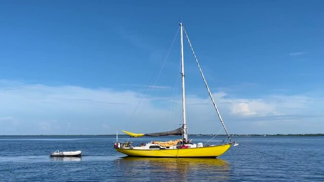 Bright yellow sailboat riding in a sea in Charlotte Harbor, Punta Gorda, FL